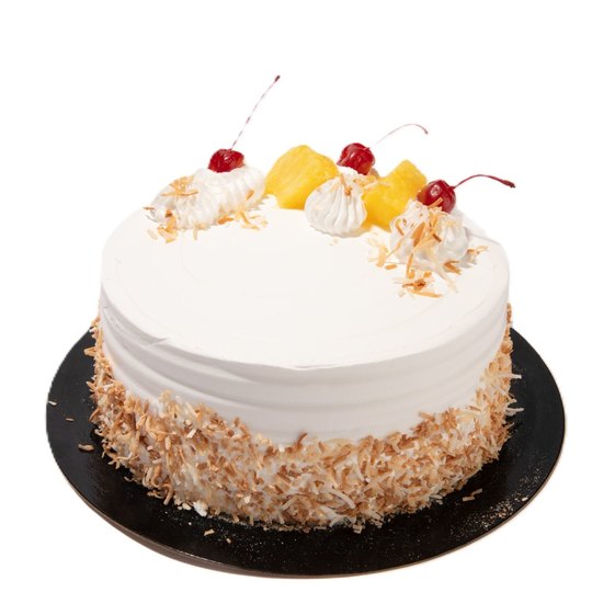 Pina colada cake with white frosting, toasted coconut sides, pineapple chunks, whipped cream, and cherries on top.
